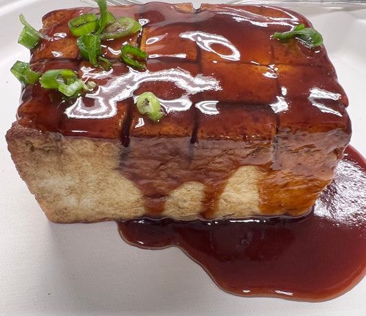 Pan Seared Tofu Steak on a bed of steamed white rice, roasted vegetables and drizzled with teriyaki sauce