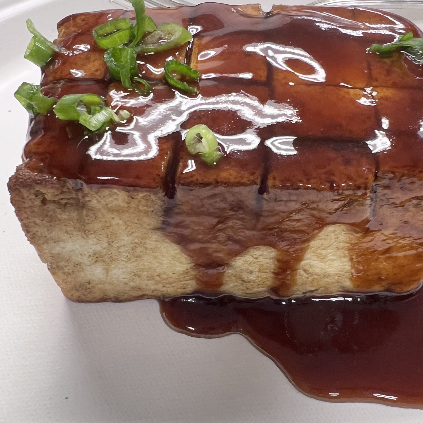 Pan Seared Tofu Steak on a bed of steamed white rice, roasted vegetables and drizzled with teriyaki sauce